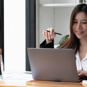 Business asian woman using laptop for do math finance on wooden desk in office, tax, accounting